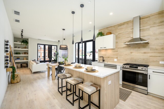 kitchen with stainless steel appliances, wall chimney exhaust hood, a center island, backsplash, and a breakfast bar