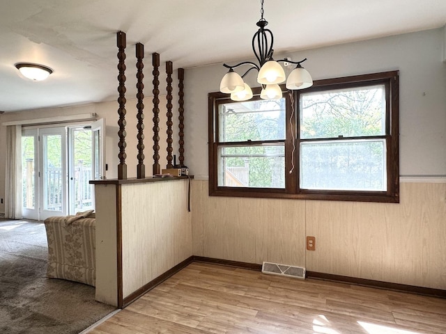 77 Briarcliff Ln, Bourbonnais, IL 60914 - unfurnished dining area with plenty of natural light, a chandelier, a wainscoted wall, light wood finished floors, and wood walls
