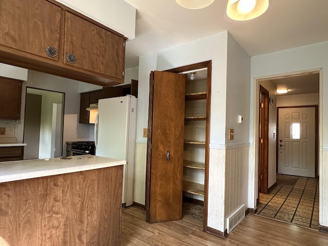 77 Briarcliff Ln, Bourbonnais, IL 60914 - kitchen featuring freestanding refrigerator, wood finished floors, light countertops, under cabinet range hood, and a wainscoted wall