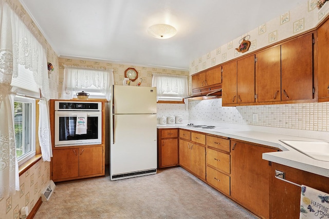 kitchen with white appliances, wallpapered walls, light countertops, brown cabinets, and a sink