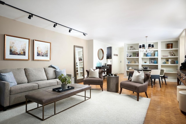 living area featuring rail lighting, a chandelier, and built in features