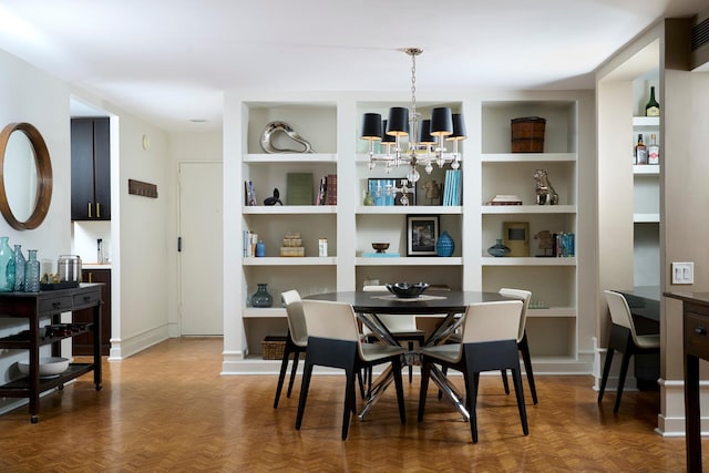 dining area with a chandelier, built in features, and baseboards