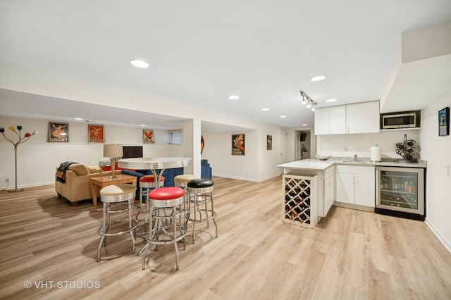 630 Juniper Rd, Glenview, IL 60025 - indoor wet bar featuring beverage cooler, stainless steel microwave, light wood-style flooring, baseboards, and recessed lighting