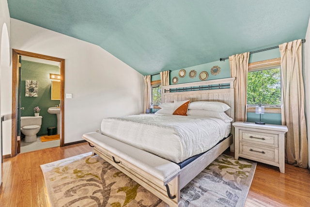 10632 Ventura Blvd, Machesney Park, IL 61115 - bedroom featuring lofted ceiling, light wood-type flooring, connected bathroom, and baseboards
