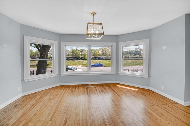 7316 S Woodlawn Ave, Chicago, IL 60619 - unfurnished dining area featuring plenty of natural light, wood-type flooring, baseboards, and a chandelier