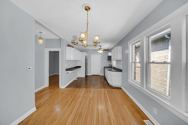 7316 S Woodlawn Ave, Chicago, IL 60619 - kitchen featuring a chandelier, white cabinetry, light wood finished floors, and baseboards