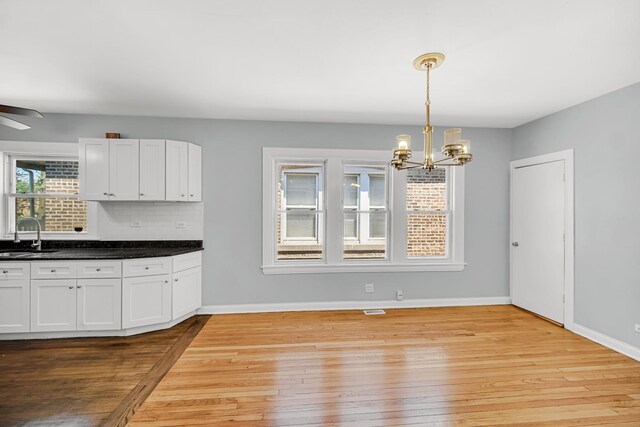 7316 S Woodlawn Ave, Chicago, IL 60619 - kitchen with wood-type flooring, a chandelier, white cabinets, and a sink