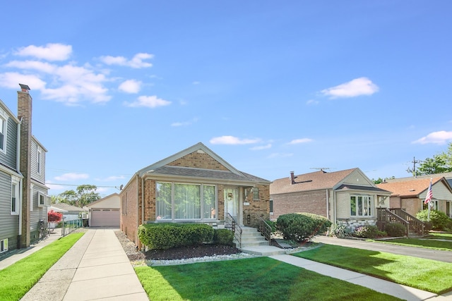 bungalow-style house featuring brick siding, a front yard, a garage, and an outdoor structure