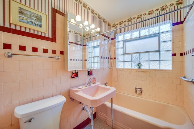 bathroom with tile walls, toilet, and tub / shower combination