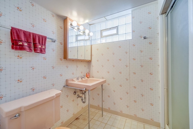 bathroom featuring toilet, baseboards, and a sink
