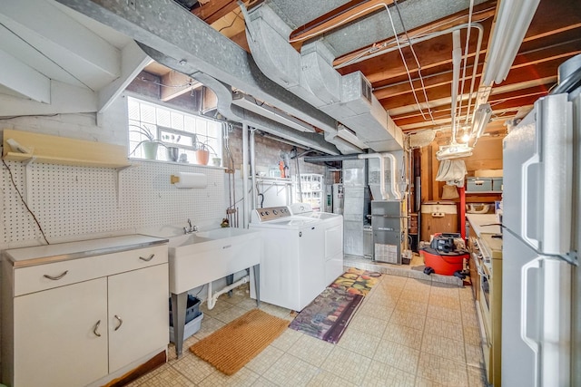 below grade area featuring independent washer and dryer, freestanding refrigerator, light floors, and heating unit