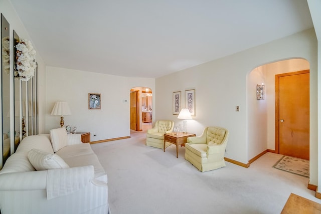 living area featuring arched walkways, carpet flooring, and baseboards