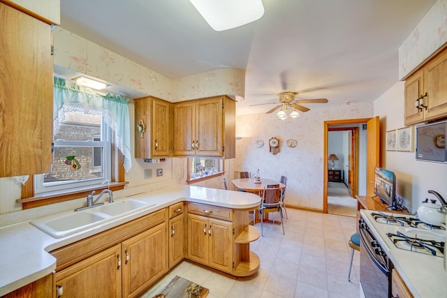 kitchen featuring wallpapered walls, a sink, a peninsula, ceiling fan, and light countertops