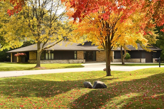 view of front of house with board and batten siding, a front lawn, and stone siding