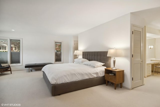 bedroom featuring light colored carpet, baseboards, and ensuite bathroom