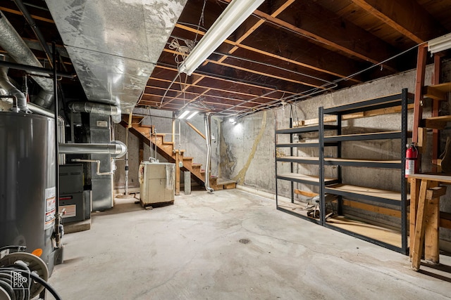 unfinished below grade area with gas water heater, stairway, and heating unit