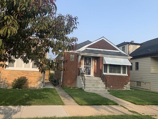 bungalow-style house featuring brick siding and a front yard