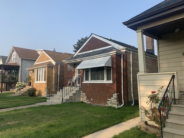 bungalow-style house featuring brick siding and a front yard