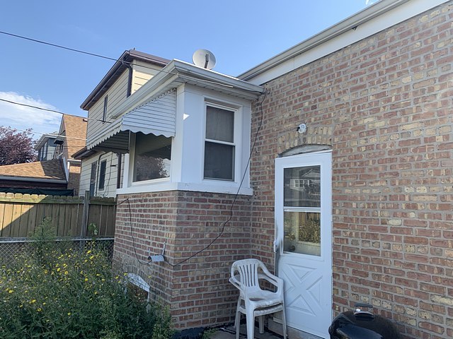 view of property exterior with brick siding and fence