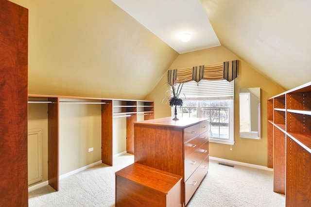 walk in closet with light carpet and lofted ceiling