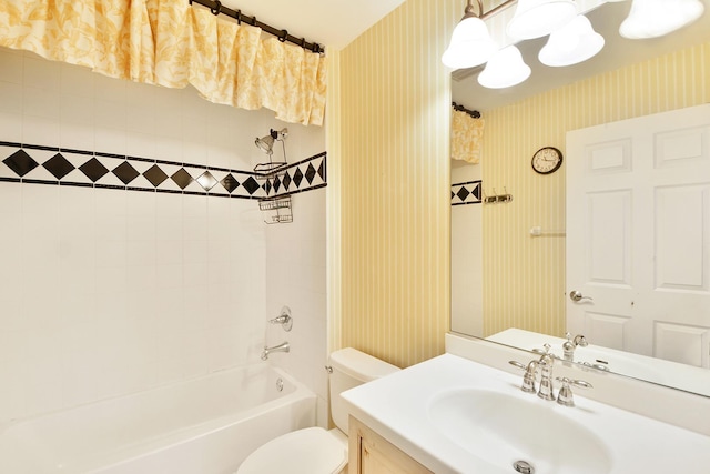 bathroom with wallpapered walls, toilet, vanity, and bathtub / shower combination