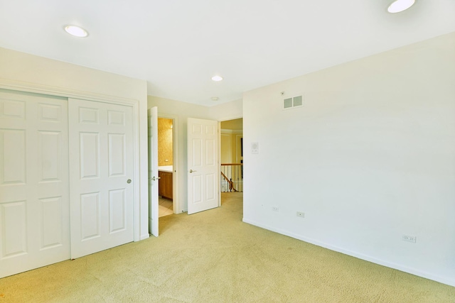 unfurnished bedroom with light colored carpet, a closet, baseboards, and recessed lighting