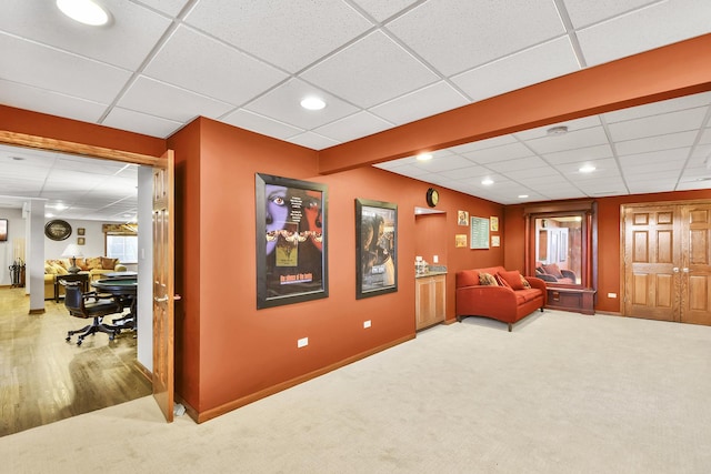living area featuring a drop ceiling, carpet, baseboards, and recessed lighting
