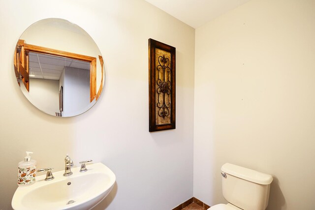 half bath featuring a sink, toilet, and baseboards