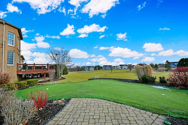 view of grassy yard with an area to practice putting and a deck