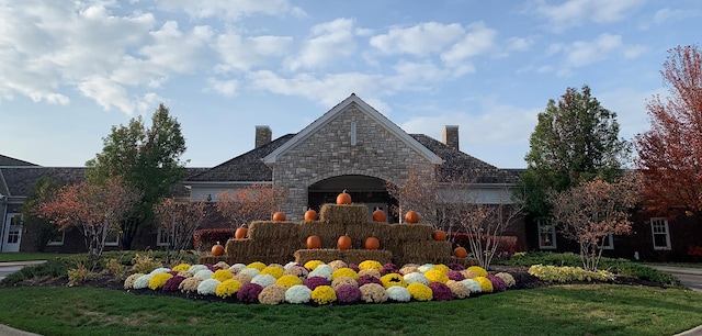 view of front of property with a chimney, a front yard, and stone siding