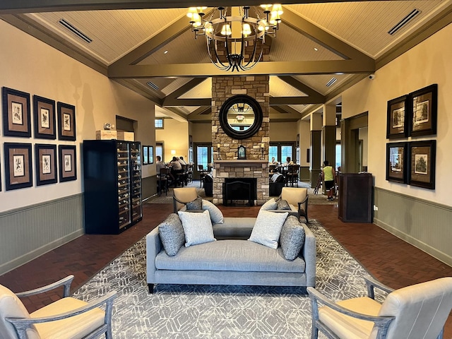 living room featuring a wainscoted wall, a chandelier, a stone fireplace, wood finished floors, and wood ceiling