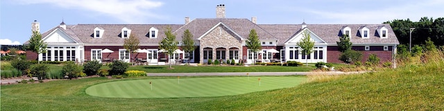 view of property's community featuring an area to practice putting and a yard