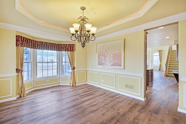 unfurnished room featuring a raised ceiling, a chandelier, healthy amount of natural light, crown molding, and stairway