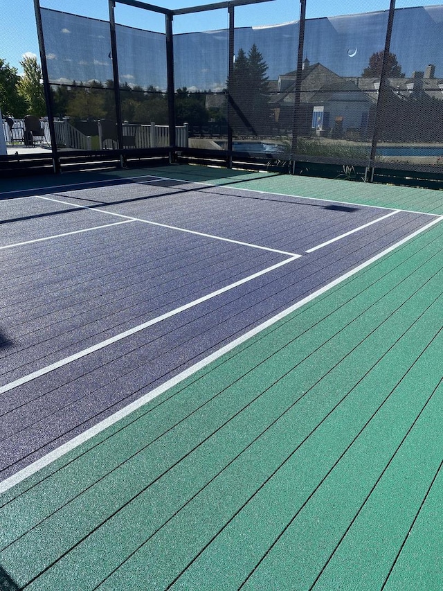 view of tennis court featuring community basketball court and fence