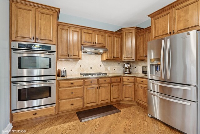 25738 W Sunnymere Dr, Plainfield, IL 60585 - kitchen with stainless steel appliances, light wood-style floors, light stone counters, tasteful backsplash, and brown cabinets