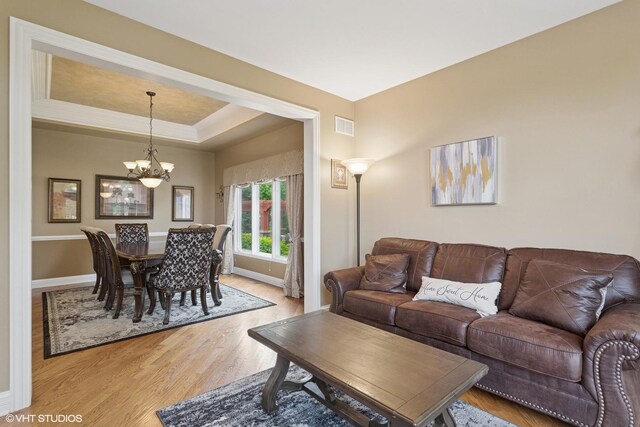 25738 W Sunnymere Dr, Plainfield, IL 60585 - living area featuring a chandelier, light wood finished floors, baseboards, and a tray ceiling