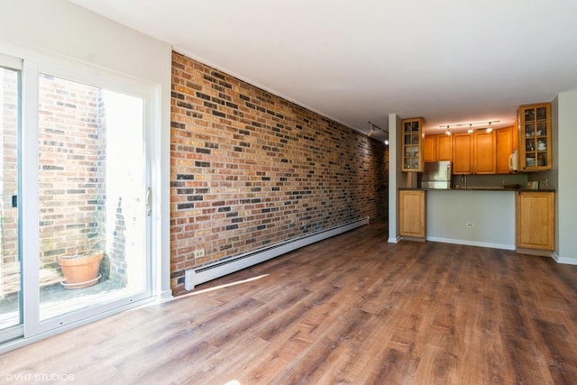 401 W Webster Ave Unit 509, Chicago, IL 60614 - unfurnished living room featuring a baseboard heating unit, dark wood-style floors, rail lighting, brick wall, and baseboards
