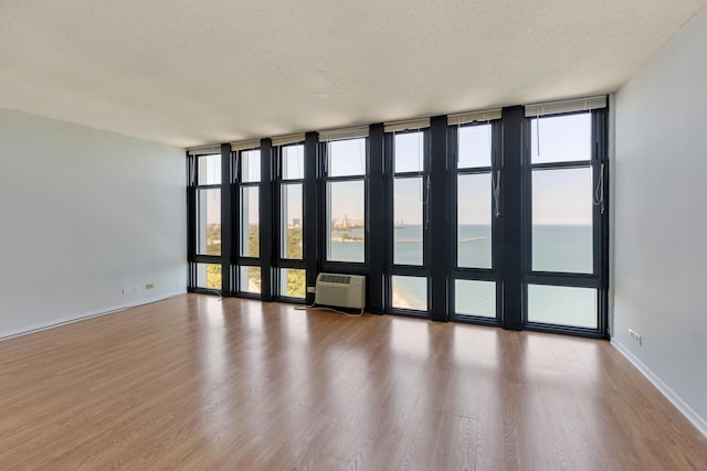6700 S S Shore Dr Unit 19K, Chicago, IL 60649 - unfurnished room featuring a textured ceiling, wood finished floors, a wall mounted AC, floor to ceiling windows, and baseboards