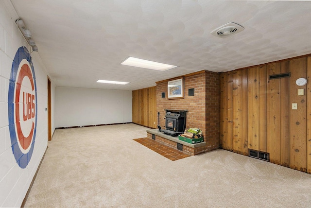 807 S Main St, Belvidere, IL 61008 - unfurnished living room featuring a wood stove, carpet, and wood walls