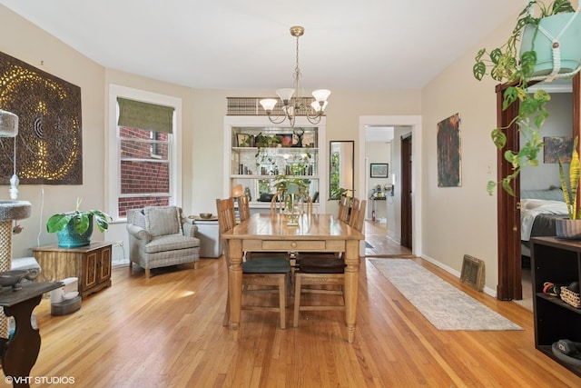 3624 N Leavitt St, Chicago, IL 60618 - dining area featuring a chandelier, light wood finished floors, and baseboards