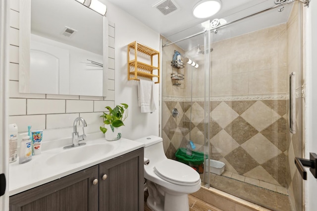 bathroom featuring toilet, vanity, a stall shower, and backsplash