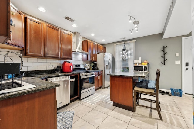 kitchen featuring stainless steel appliances, wall chimney exhaust hood, backsplash, a kitchen bar, and a kitchen island