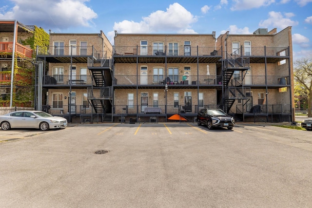 view of apartment building / complex featuring stairs and uncovered parking