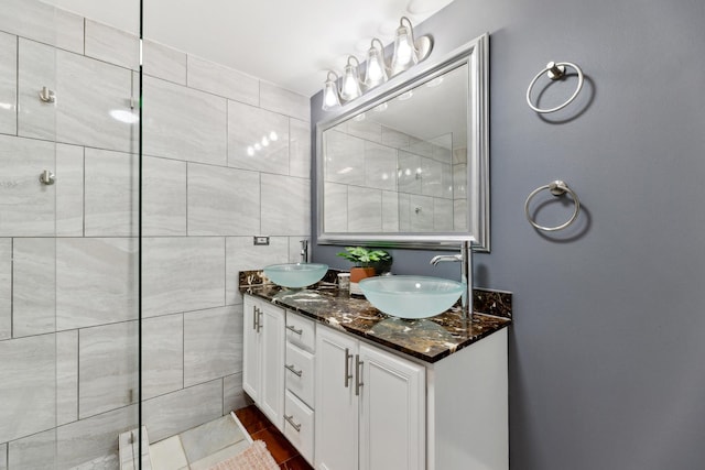 bathroom with a tile shower and double vanity