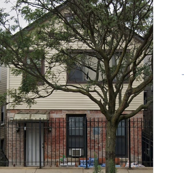 view of front of home with brick siding and fence