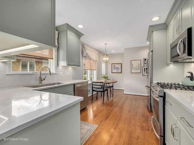 kitchen featuring appliances with stainless steel finishes, a sink, tasteful backsplash, a chandelier, and recessed lighting