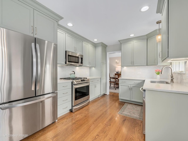 kitchen with stainless steel appliances, a sink, light wood-style flooring, tasteful backsplash, and recessed lighting