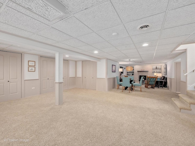 finished below grade area featuring carpet, stairs, a paneled ceiling, recessed lighting, and wainscoting