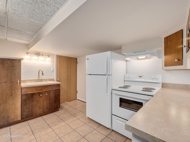 kitchen with white appliances, under cabinet range hood, a sink, light countertops, and backsplash
