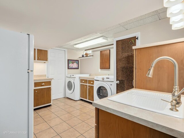 laundry room with cabinet space, light tile patterned flooring, and washer and clothes dryer